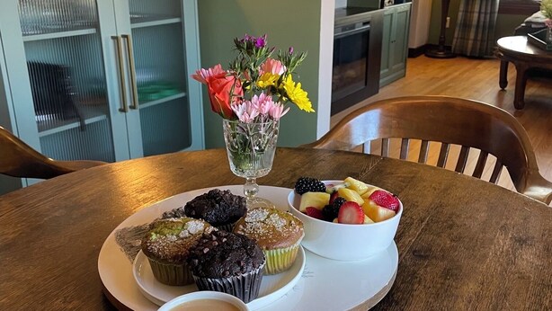 Ein Esstisch mit einer Muffinstasse, einer Obstschale und zwei Kaffeetassen.