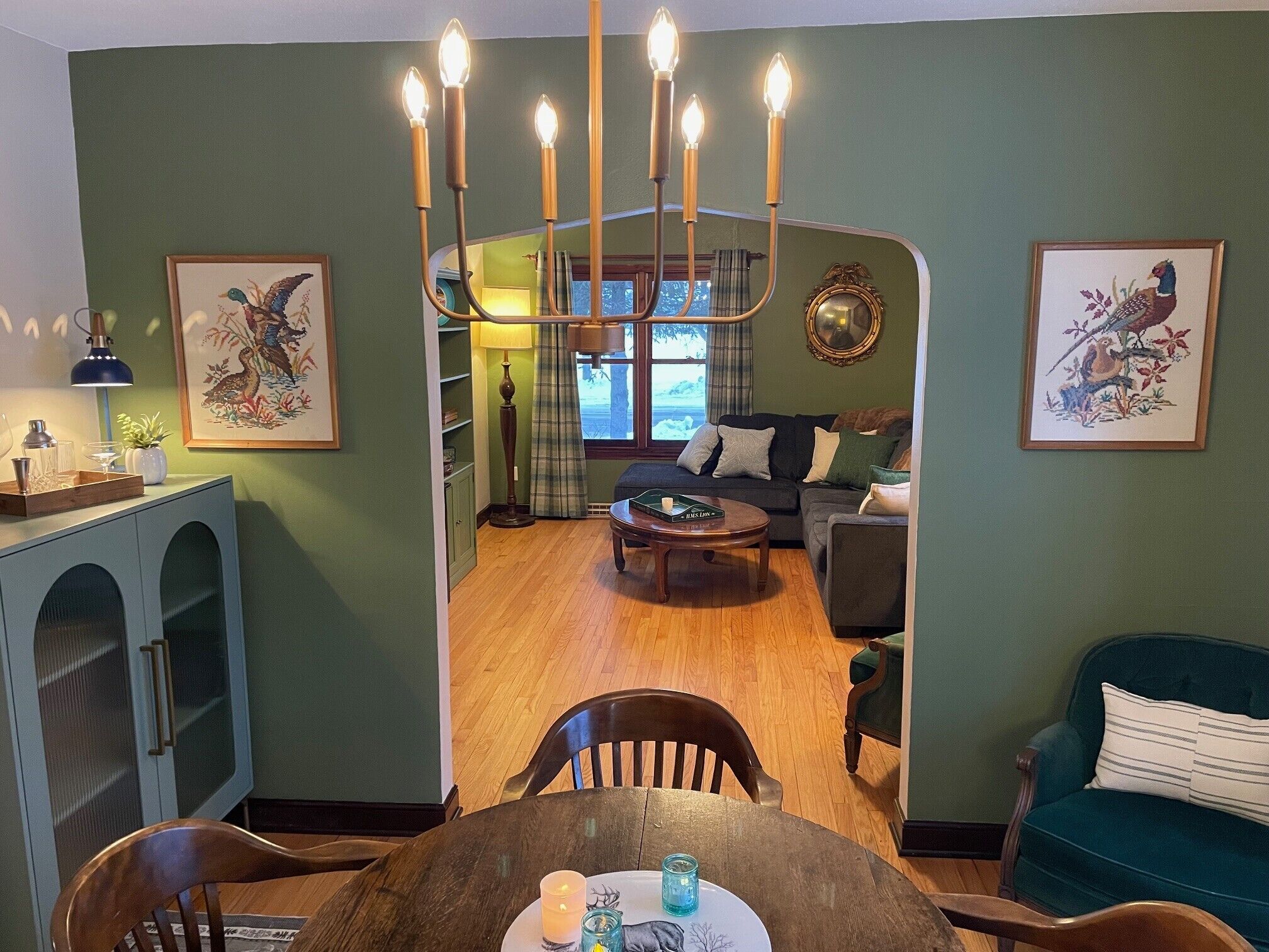 Il y a une salle à manger avec une table en bois, des chaises et un lustre. On y trouve également un salon avec un canapé et une table basse.
