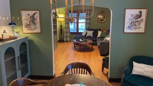 Ein Essbereich mit einem Holztisch, Stühlen und einer Deckenleuchte. Es gibt ein Wohnzimmer mit einer Couch und einem Couchtisch.