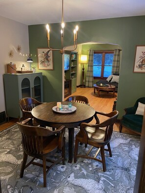 Un coin repas avec une table ronde, des chaises, un buffet et un téléviseur en arrière-plan.