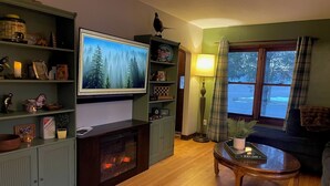 Ein Wohnzimmer mit Kamin, Fernseher und einem fensterbepflegten Fenster.