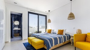 Un dormitorio moderno con una cama grande, un sillón amarillo y vistas a través de un ventanal corredera.