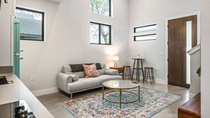 Een moderne woonkamer met een grijze bank, een ronde salontafel en een vloerkleed met dessin.