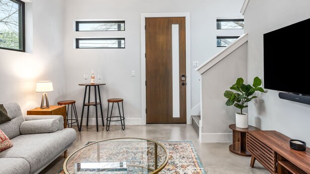 Een moderne woonkamer met een bank, salontafel en een televisie aan de muur.