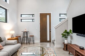 Ein modernes Wohnzimmer mit einer Couch, einem Couchtisch und einem an der Wand befestigten Fernseher.
