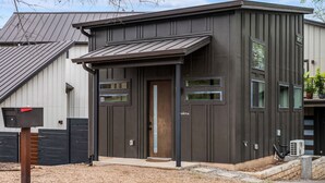 Een modern gebouw met een donkere gevel, een voordeur en een klein portaaltje.