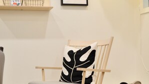 A wooden chair with a leaf-pattern pillow, a small round wooden table, and a woven basket on the floor. - Skovhaven West Coast Suite in Upper Gibsons, minutes away from the beach & more! (Gibsons)
