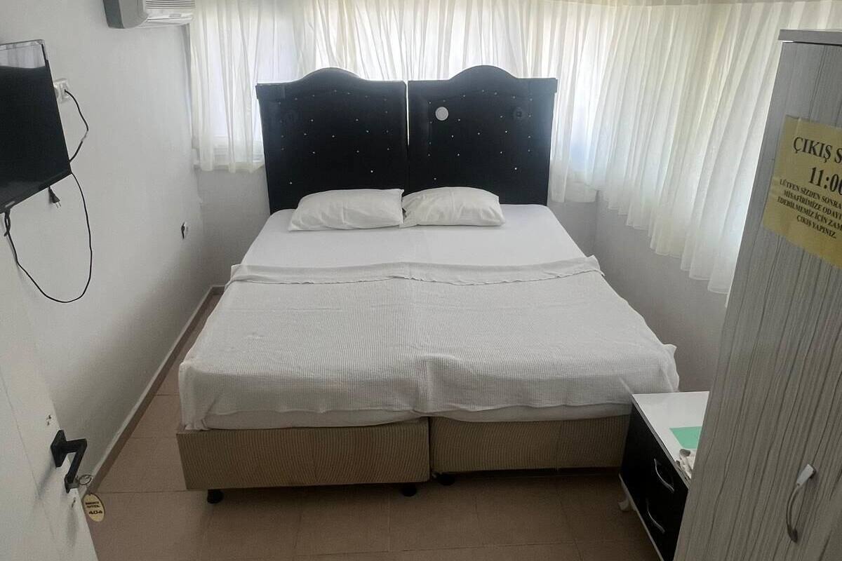 Uma cama de solteiro com cabeceira, mesa de cabeceira, guarda-roupa e ar condicionado fixado na parede.