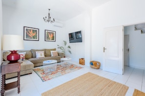 A living room with a sofa, coffee table, rug, and artwork on the wall. - Casa no Limoeiro, Stylish Retreat (Loulé)
