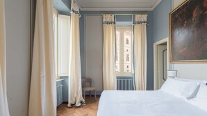 A bedroom with a bed, a chair, a radiator, and a window with curtains. - Vista Ara Pacis, lussuoso appartamento centro di Roma 5 min da Piazza di Spagna (Roma)