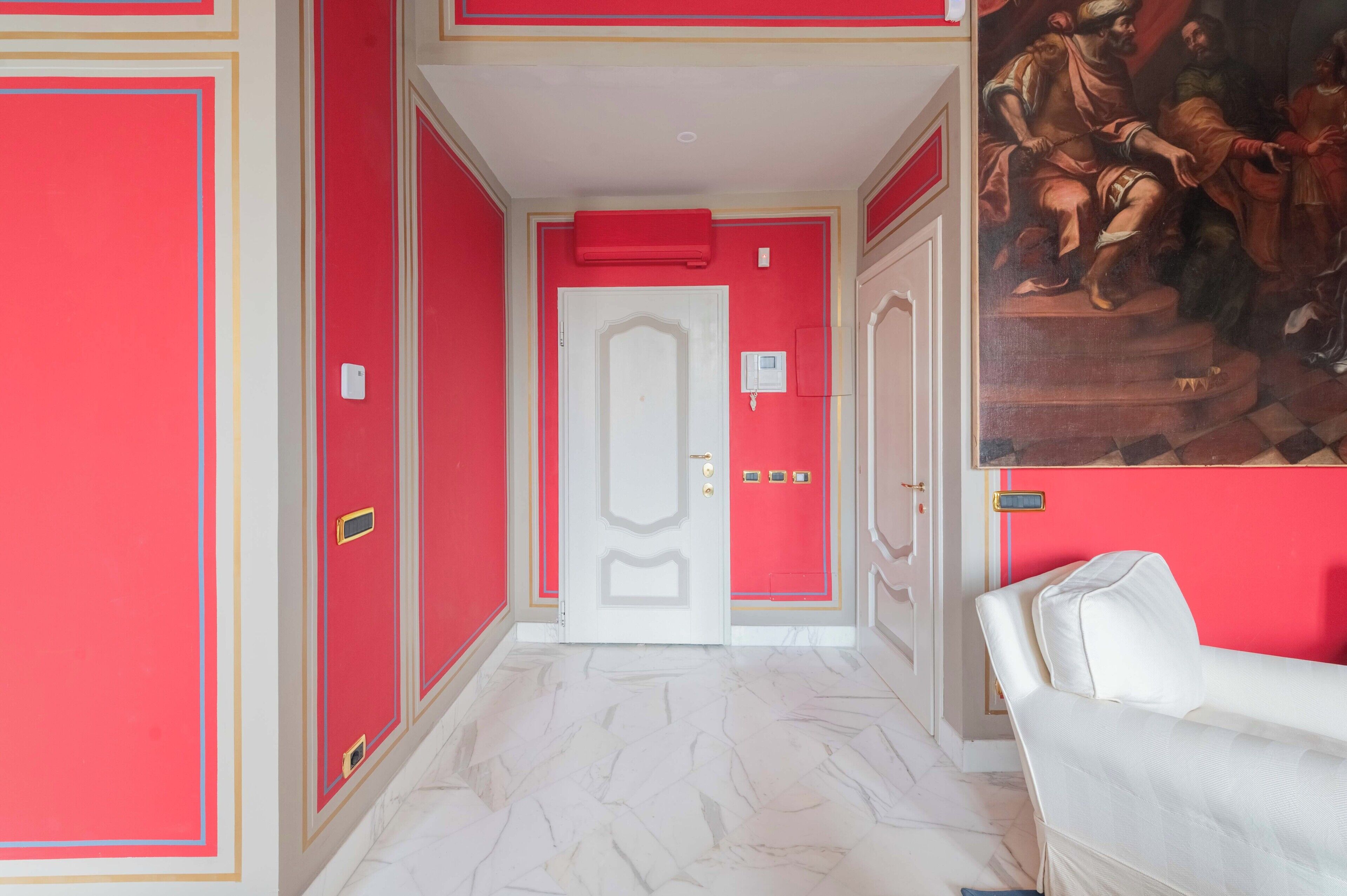 A hallway with red walls, a white door, and a white sofa.