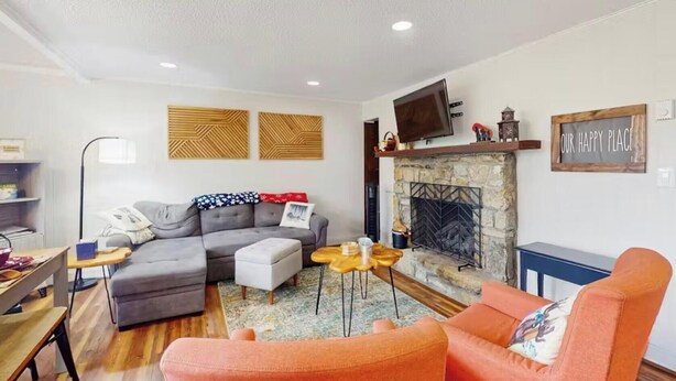 Una sala de estar con sofá gris, sillón naranja y chimenea.