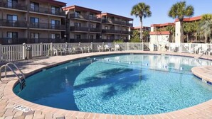 A swimming pool with a brick border, surrounded by a fence, and adjacent to a multi-story building with balconies. - NEWLY LISTED! Oceanfront and BREATHTAKING views! 3 bedrooms (North Myrtle Beach)