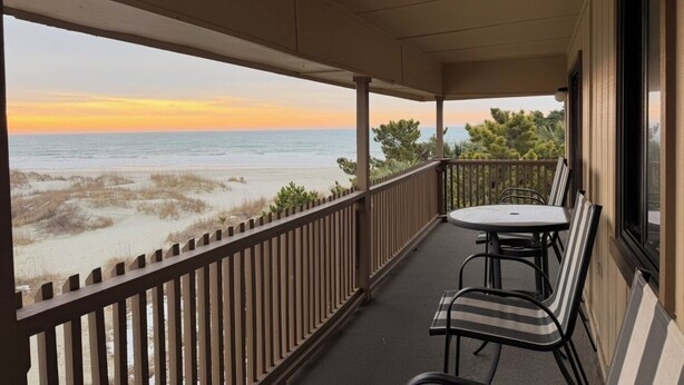 A balcony with a table and chairs, overlooking a beach with dunes and the ocean. - NEWLY LISTED! Oceanfront and BREATHTAKING views! 3 bedrooms (North Myrtle Beach)