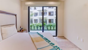 A bedroom with a bed, a nightstand, a window with a view of a building and greenery. - Pacific coast retreat w/ kayak, bikes & pool (Tondoroque)