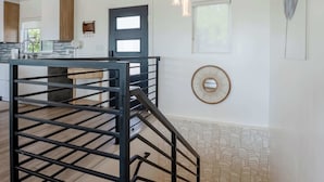 Eine Küche mit Kochinsel, Treppe und einem wandmontierten Spiegel.