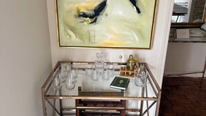 A glass-top console with wine glasses, a book, and decorative items. - The Coventry — A Family Retreat Near LSU 4BR/2BA w Game Room & Basketball Goal (Baton Rouge)