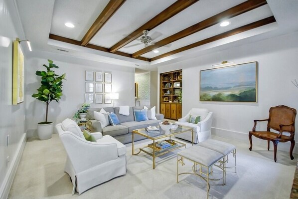 Una sala de estar moderna con un sofá, sillones, una mesa de centro, una estantería y un cuadro en la pared.
