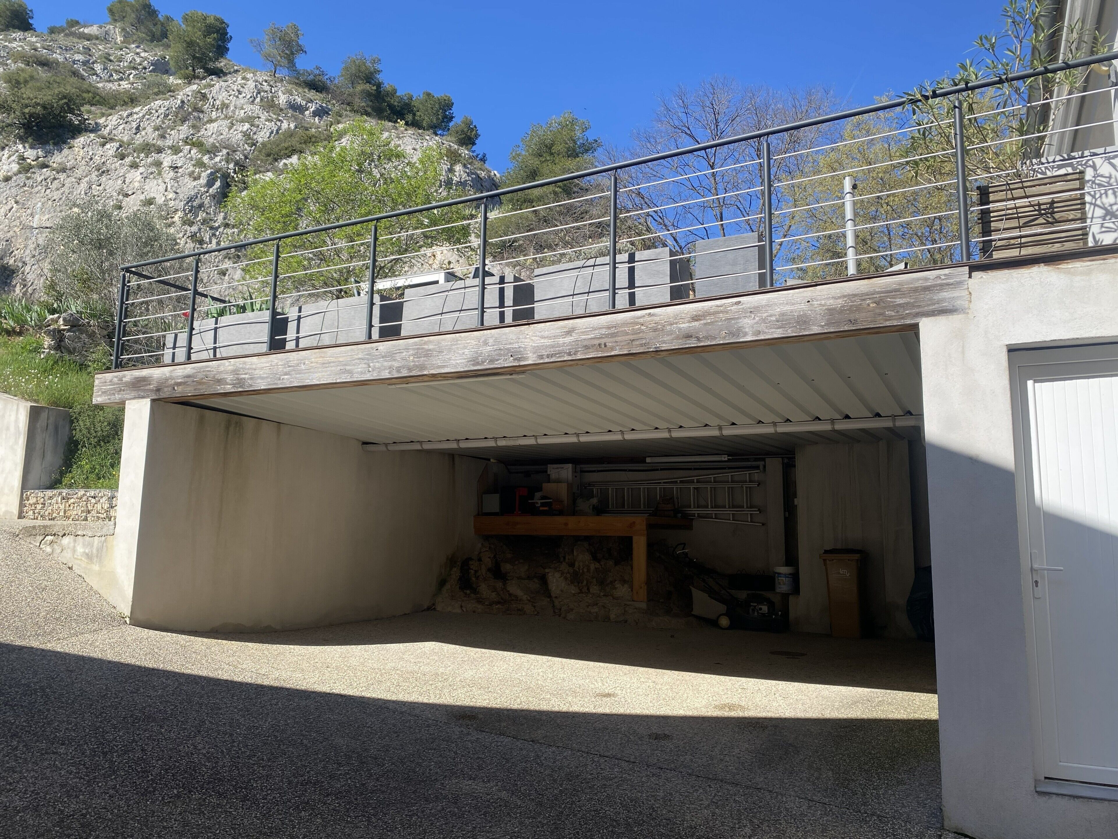 Um edifício com área externa coberta, guarda-corpo de metal e entrada para garagem.