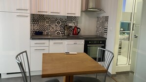 A kitchen with white cabinets, a black and white patterned backsplash, a stainless steel range hood, and a dishwasher. - Quiet studio at the foot of St Jacques hill,a stone's throw from the city center (Cavaillon)
