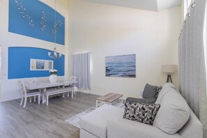 A living room with a dining table, a sofa, a painting, and a lamp. - Sunset Paradise Villa | Private South Facing Pool & Spa | Near Disney (Davenport)