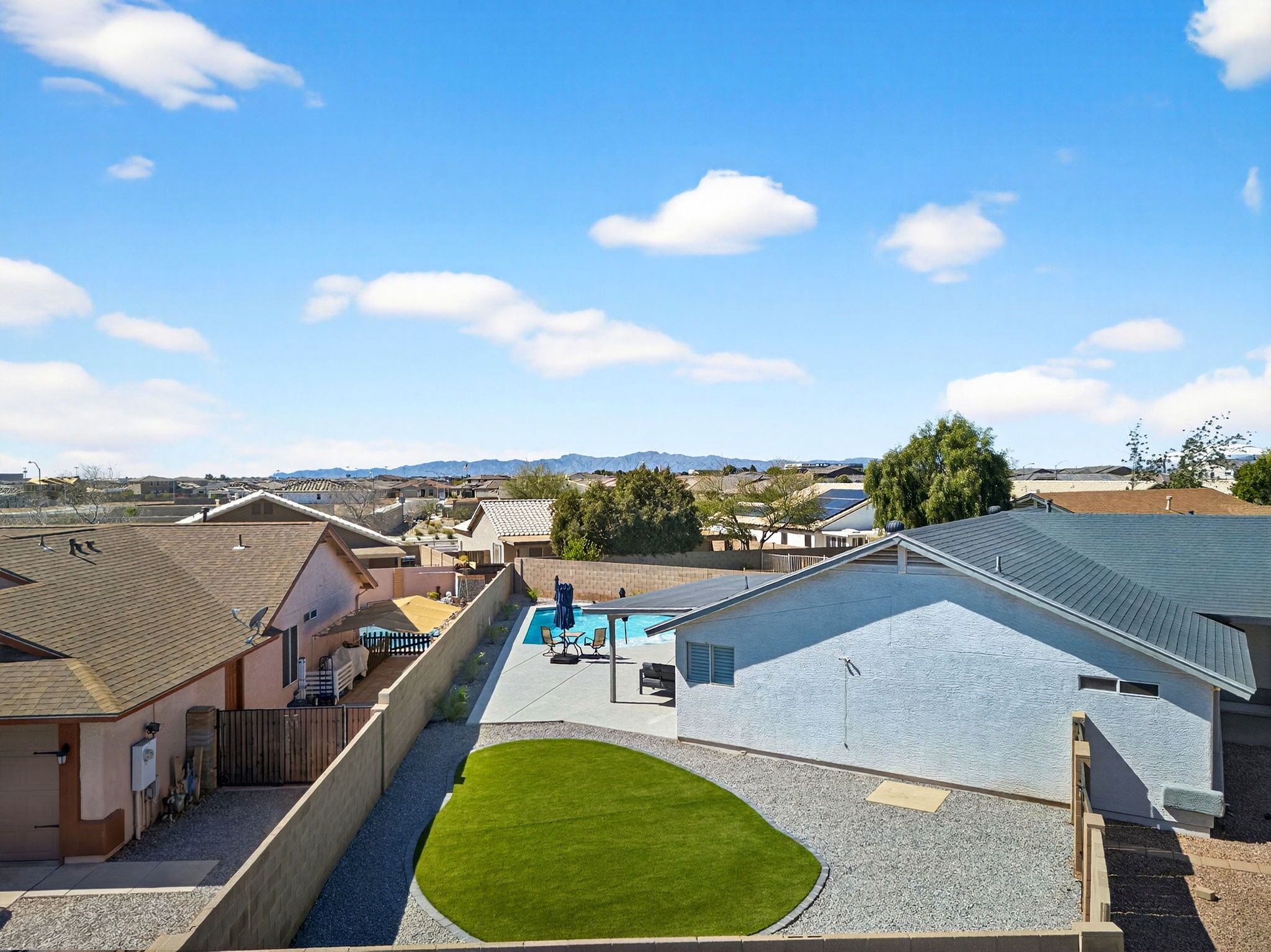 Un quartier résidentiel doté d’une piscine, d’une pelouse verdoyante et de maisons aux styles de toits variés.