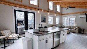A modern kitchen with a central island, built-in appliances, and large windows. - Modern Butterfly - Stylish 3 Bed 3 Bath with Hot Tub! Rumbling Bald Amenities! (Lake Lure)