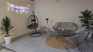 Una habitación con una silla colgante, una mesa redonda y dos macetas.