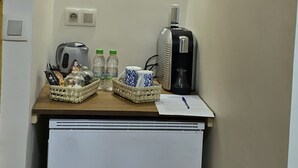 Una kitchenette con cafetera, hervidor y dos cestas sobre una encimera.