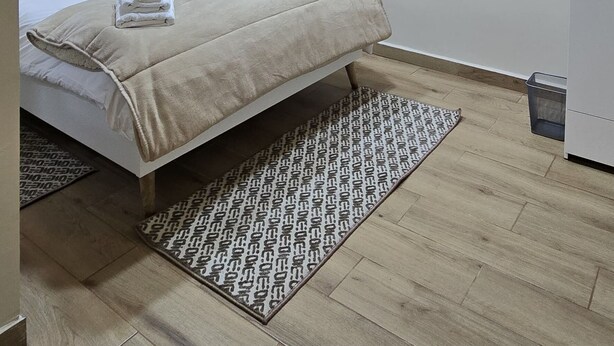 Habitación de hotel con cama, equipo de aire acondicionado, luz de techo y alfombra estampada.