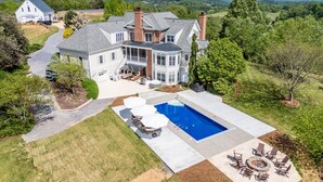 Uma casa grande com piscina, área de estar externa e vista para montanhas.