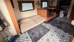 En kompakt autocamper indretning med en sofa, et lille tekøkken og et fjernsyn.