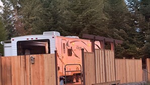 En campingvogn med garageport, lille veranda og træhegn.