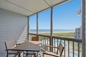 A balcony with a table and chairs, a pool, and a view of the beach and ocean. - Atlantic Beach Dream Beach Getaway (Atlantic Beach)