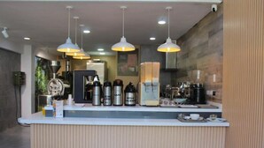 A reception area with a counter, coffee machines, and a coffee press. - HOTEL GENOVA PRADO (Barranquilla)