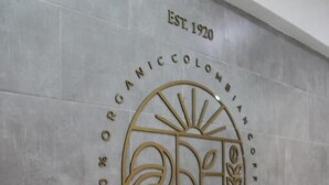 A wall with a logo and text for Santa Barbara Coffee Farm & Roaster, established in 1920, featuring a sun and coffee bean design. - HOTEL GENOVA PRADO (Barranquilla)