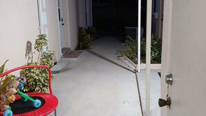 A narrow concrete pathway leading to a house with a garage door open, a toy car, and potted plants. - - Love and Tranquility (Room E and Room C)  (Tampa)