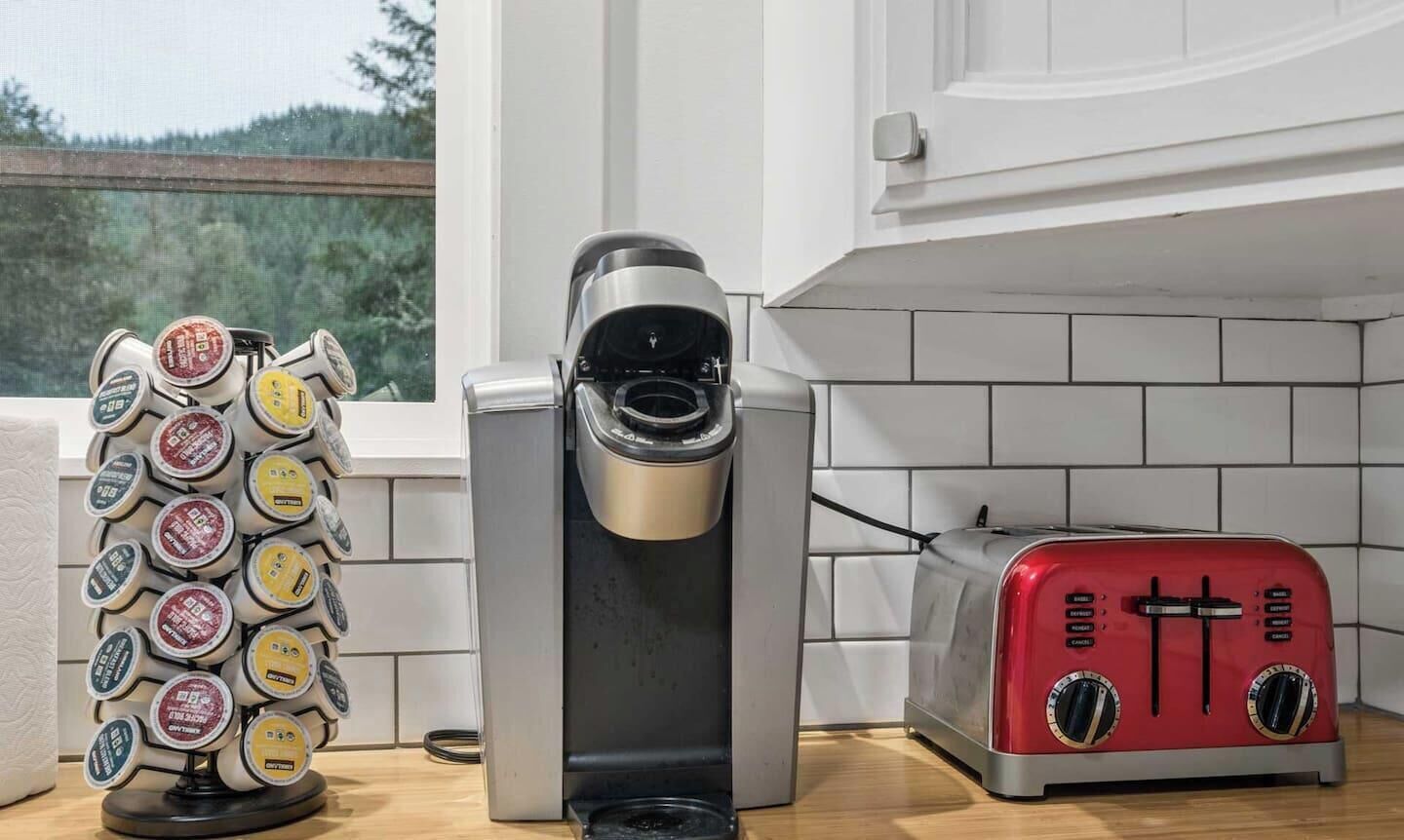 Une cuisine équipée d’une machine à café, d’un grille-pain et d’un support à capsules de café.