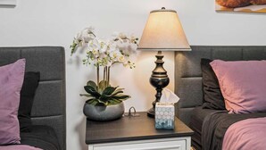 A neatly arranged hotel room with a bed, a bedside table with a lamp, a vase with flowers, and a tissue box. - Forest River Farmhouse Retreat (Fall Creek)