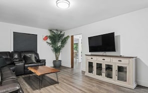 A living room with a sofa, coffee table, TV, cabinet, and a potted plant. - Forest River Farmhouse Retreat (Fall Creek)
