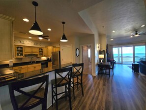 A spacious kitchen with wooden cabinets, a central island, and pendant lighting. - Shore Sounds Good (Rodanthe)