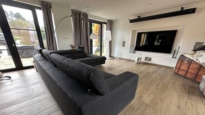 Uma sala de estar moderna com um sofá modular, uma televisão de tela plana e piso de madeira.