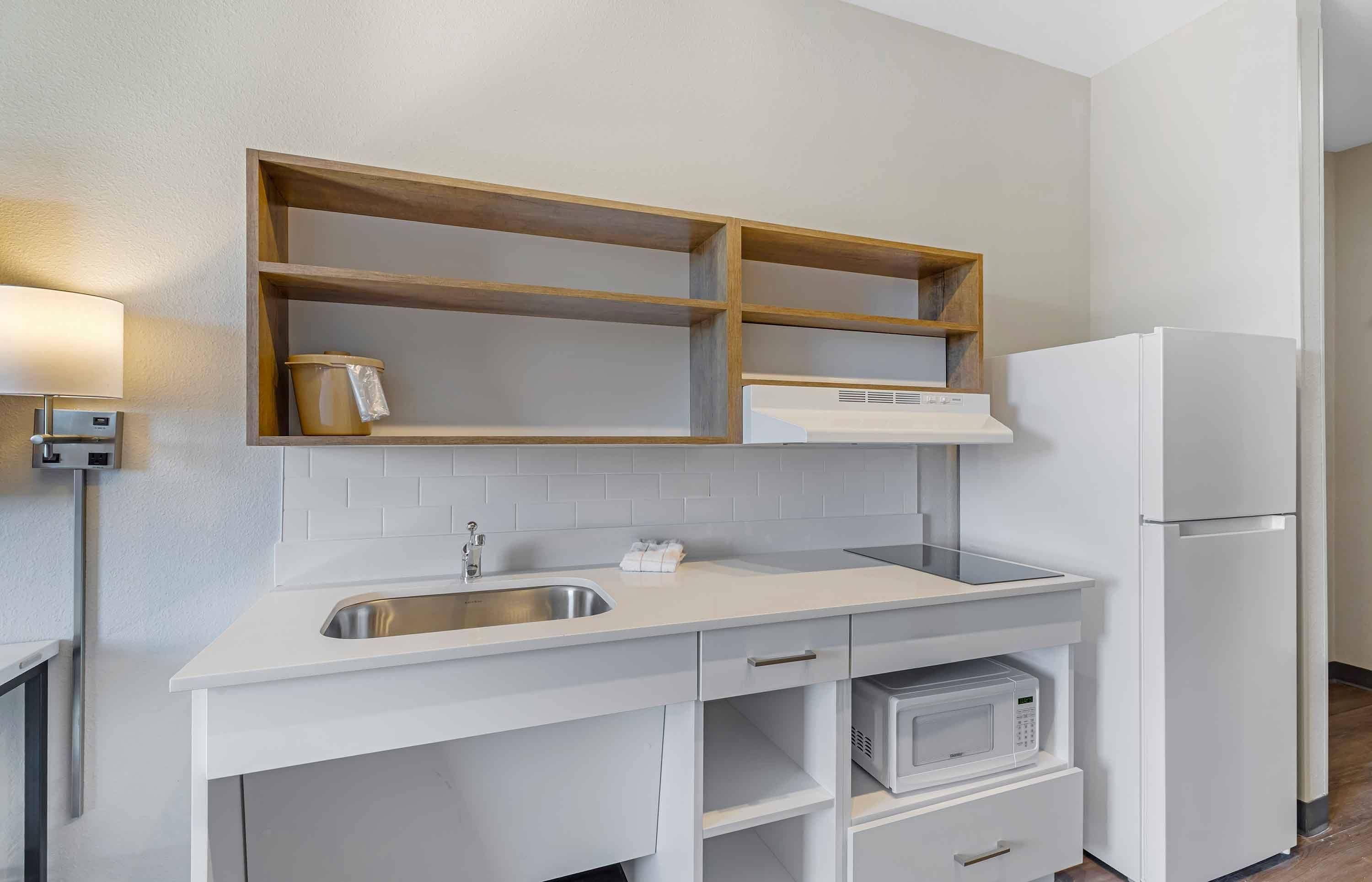A kitchen with a built-in microwave, a stainless steel sink, and a white refrigerator.