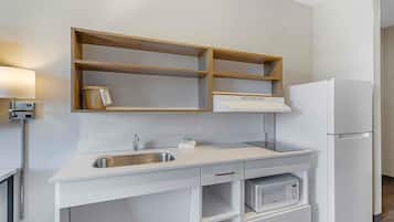 A kitchen with a built-in microwave, a stainless steel sink, and a white refrigerator.