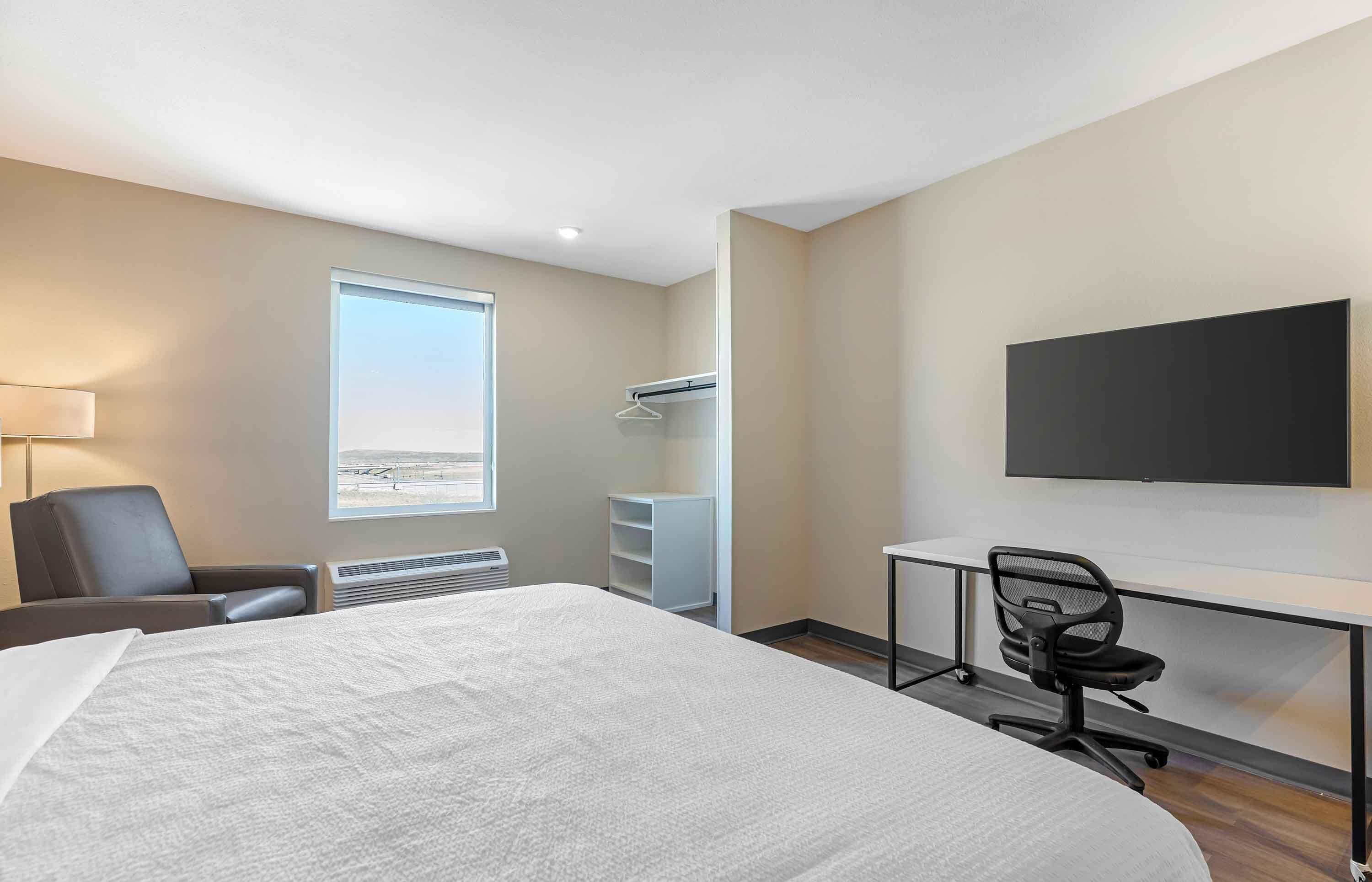 Habitación de hotel con una cama grande, un escritorio, una silla, un televisor, una ventana con vistas y un armario.