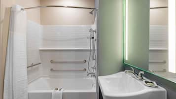 Un baño moderno con ducha a ras de suelo, bañera, lavabo y espejo con luz verde.