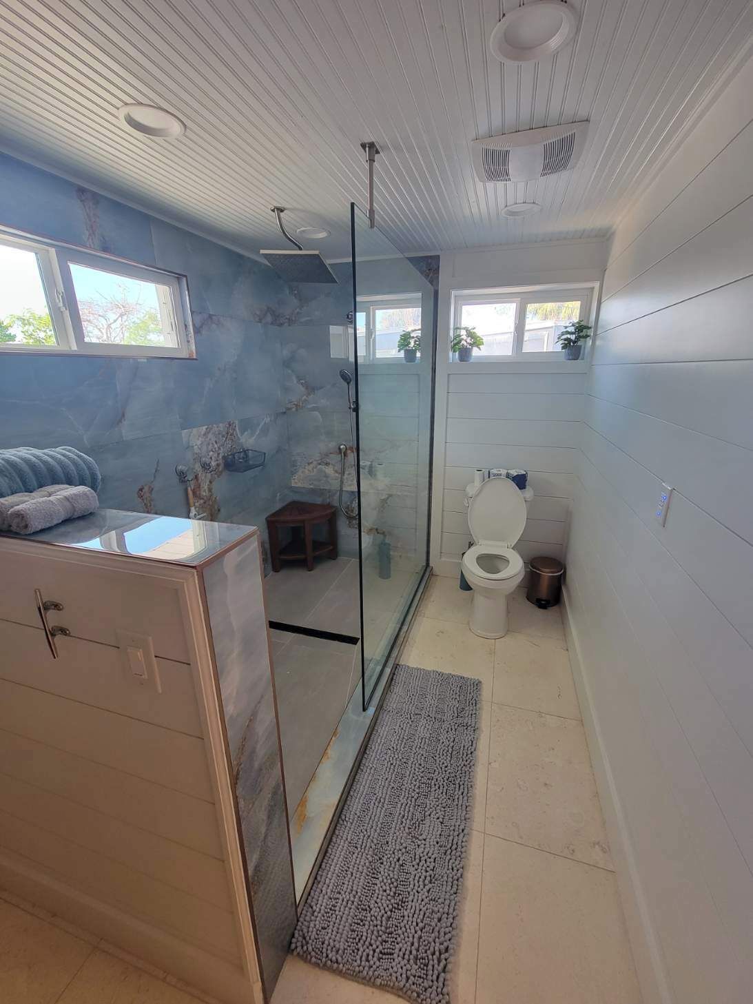 Een badkamer met een douchecabine van glas, een toilet, een wastafel en een kast.