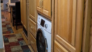 Un'area lavanderia con armadietti in legno, una lavatrice e un tappeto decorato.