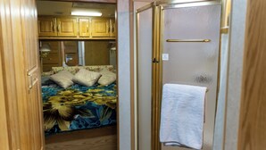 Interni di un camper compatto con letto, angolo cottura e bagno.