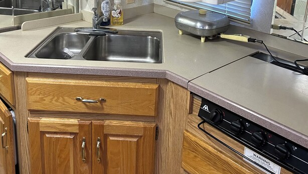 Una cucina con mobili in legno, un lavandino in acciaio inox, una macchina da caffè e un forno a microonde.